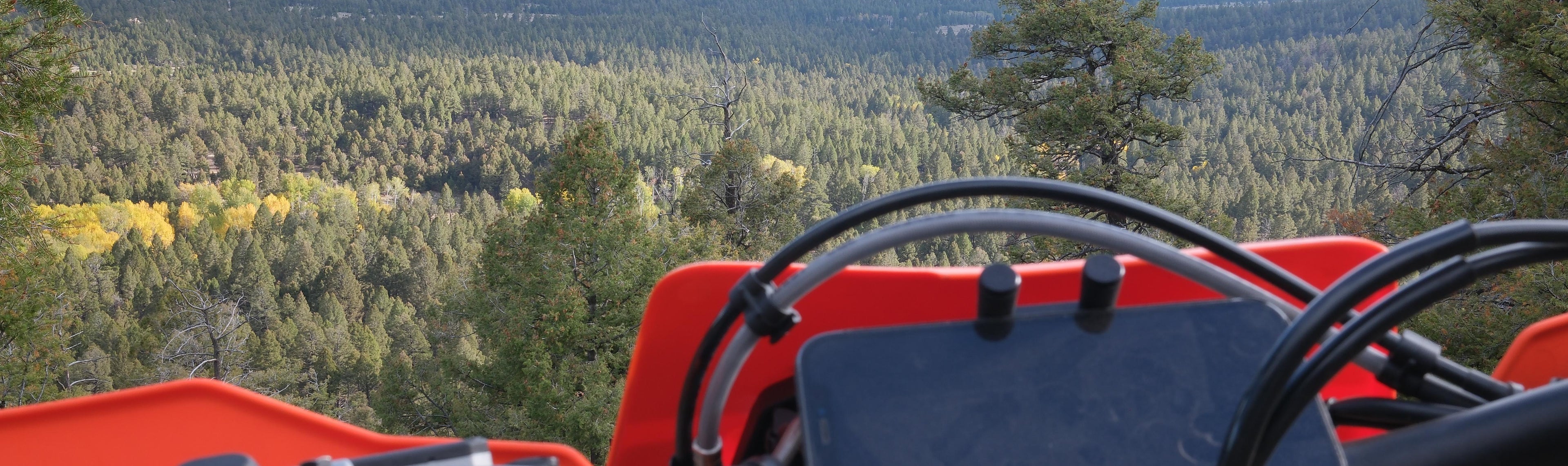 Motorcycle handlebar with a scenic view of a forest and mountains in the background featuring the perfect squeeze phone mount on a ktm 300xc-w xc dirtbike husqvarna